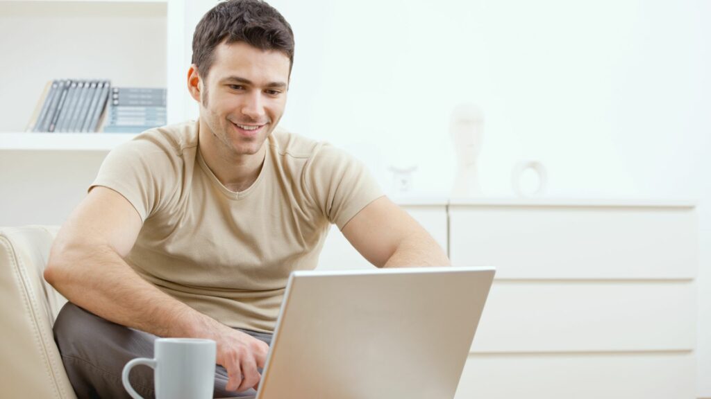 Imagem de um homem feliz usando computador, trazendo o conceito de uma relação de refúgio com a máquina.