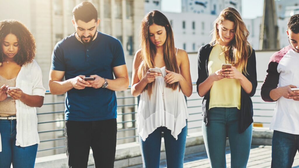 Imagem de um grupo de pessoas, com celulares em mãos, discutindo rumos das novas tecnologias e das IA's.

