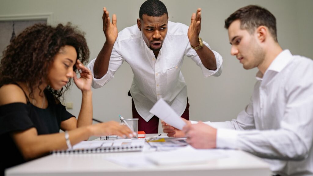 Imagem de um homem irritado em um local de trabalho, simbolizando a manipulação entre os funcionários.

